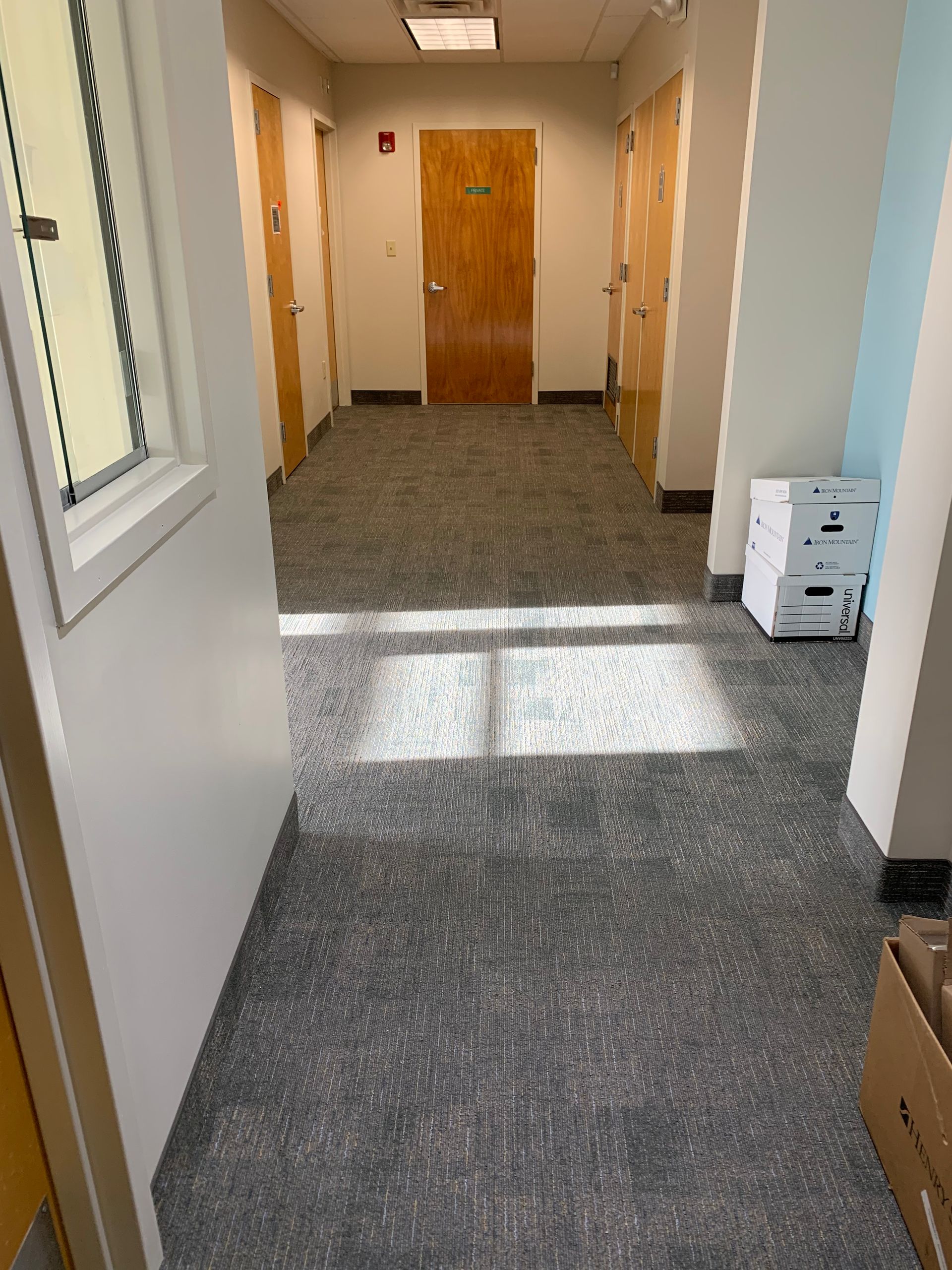 A hallway with boxes on the floor and a window