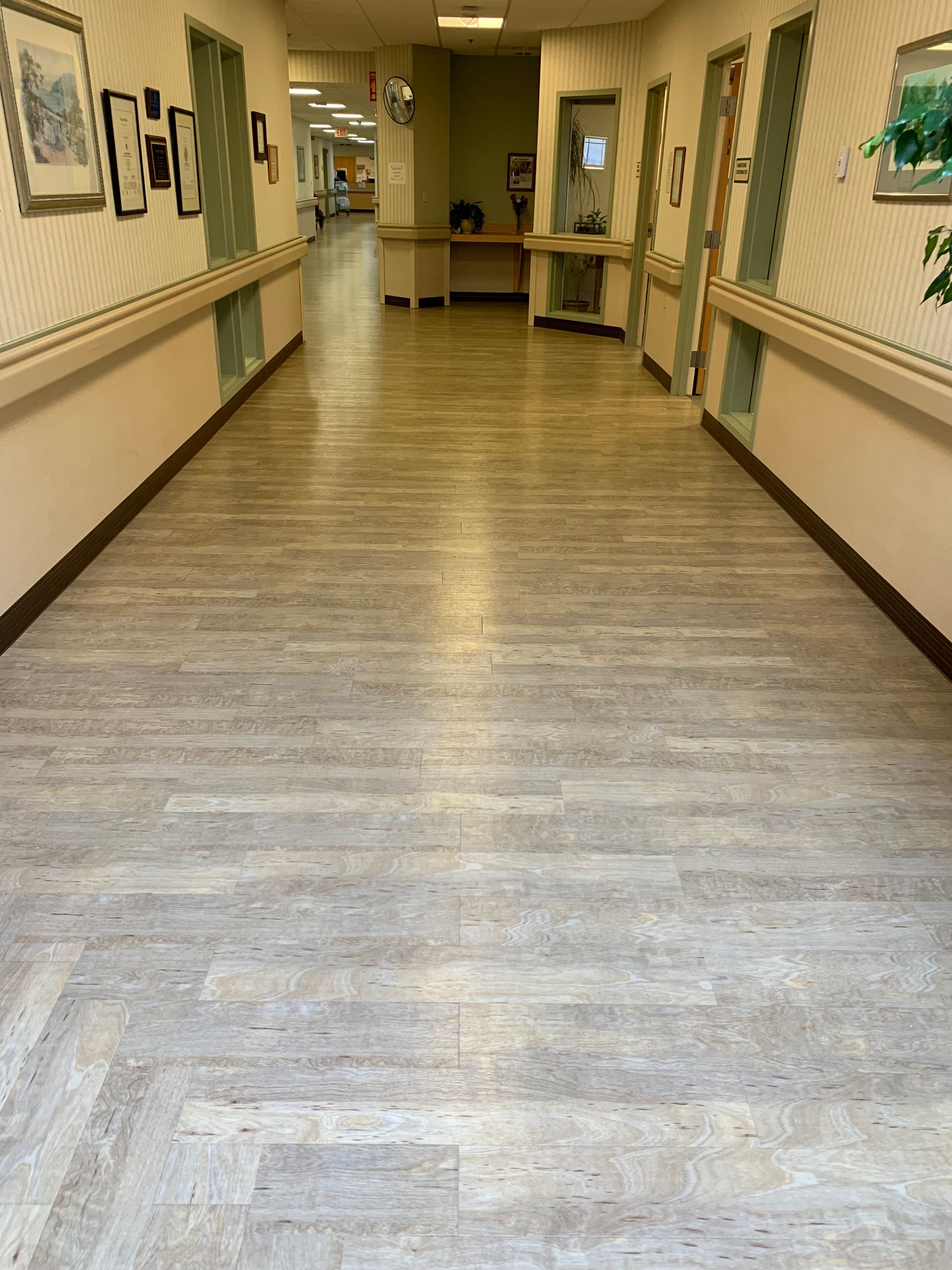 A long hallway in a hospital with a wooden floor