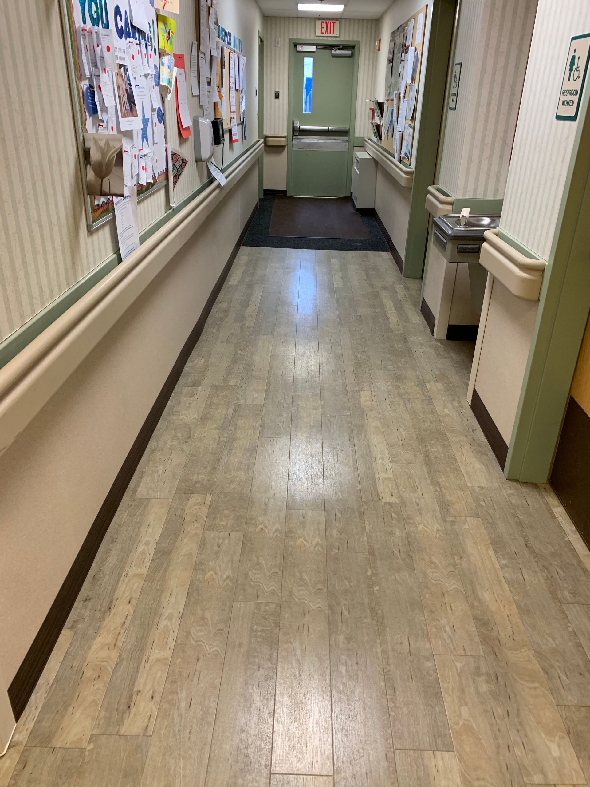 A long hallway in a hospital with a bulletin board on the wall