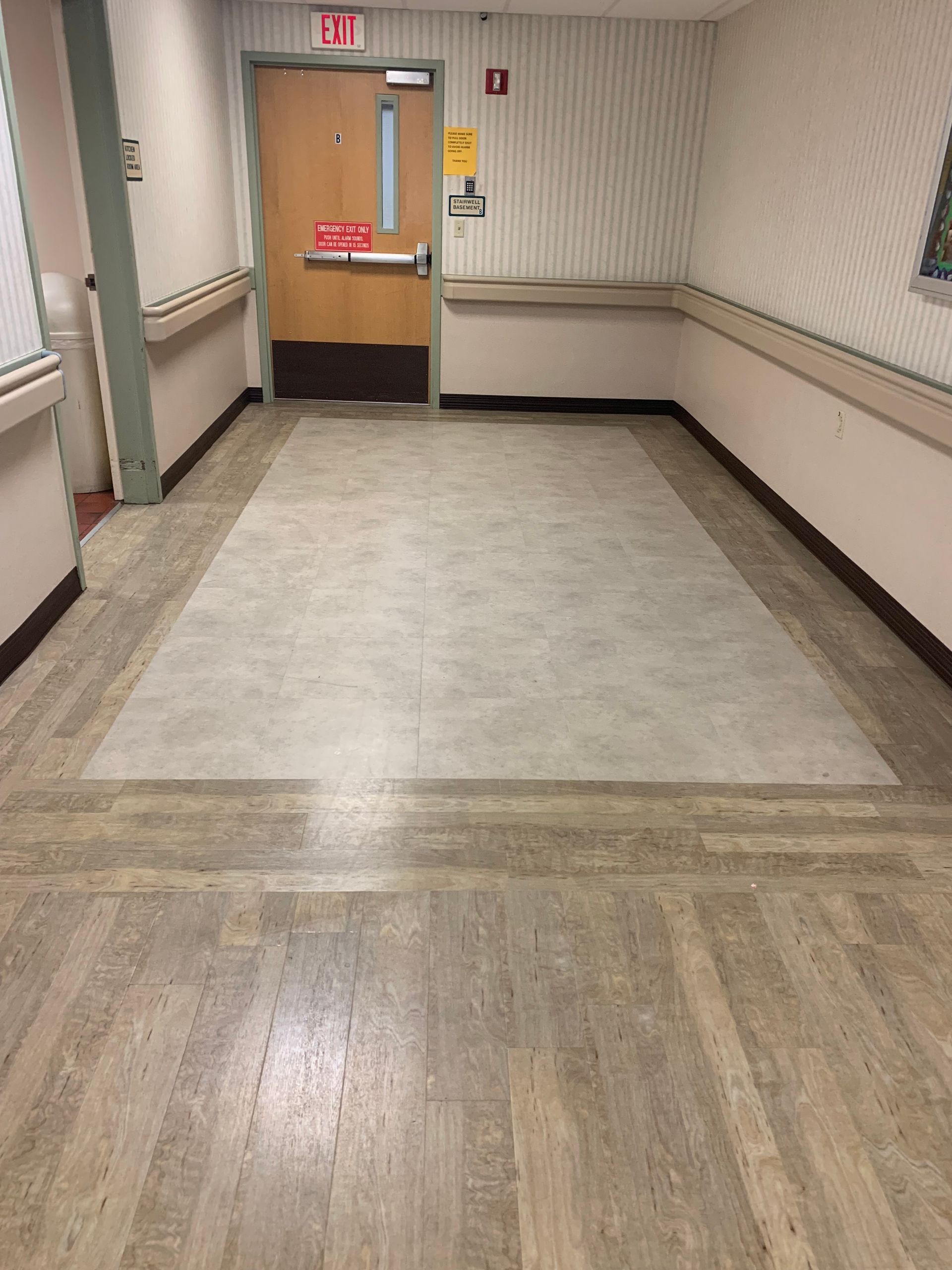 A hallway with a red exit sign on the door