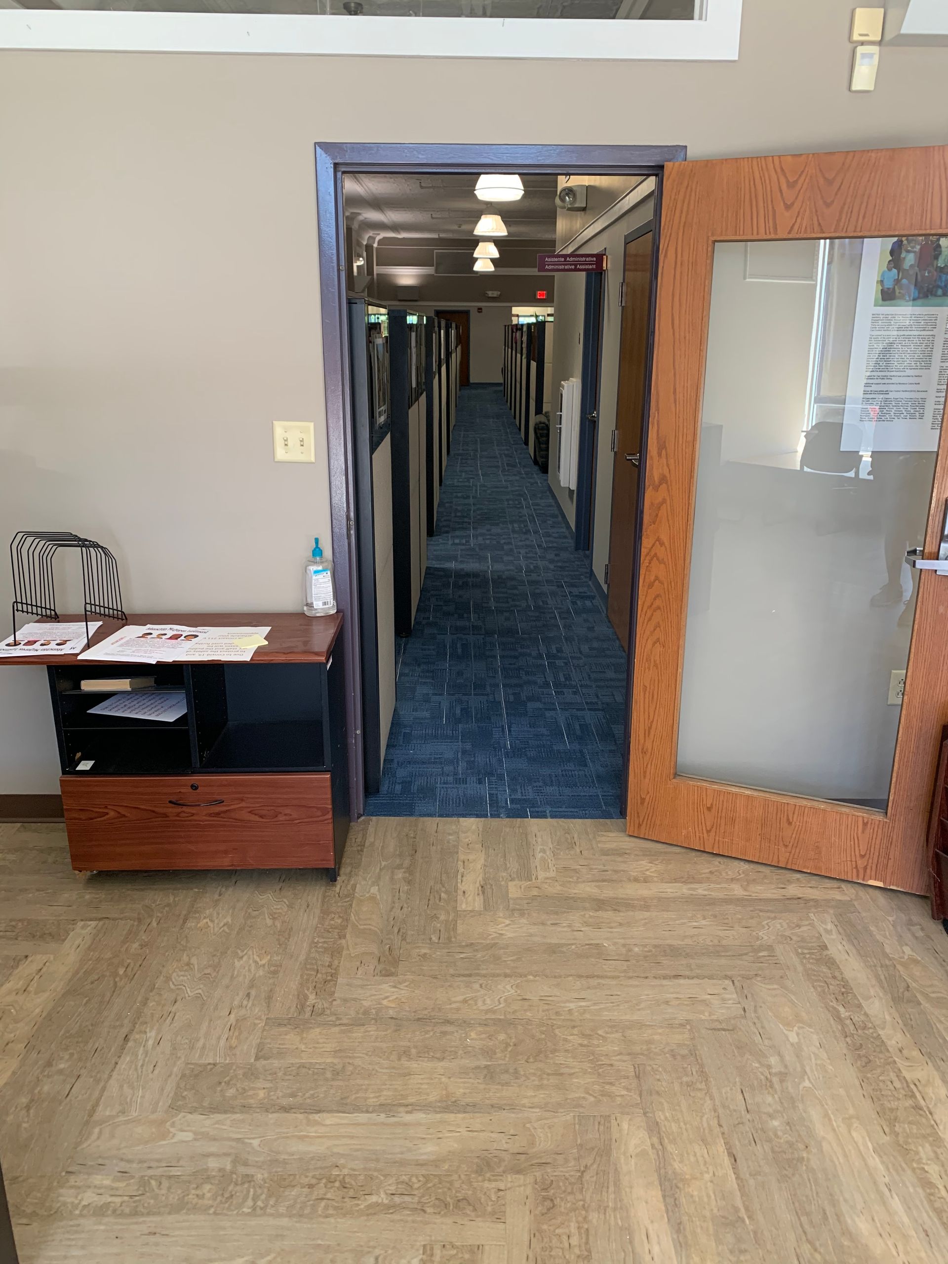 A long hallway with a glass door leading to a room