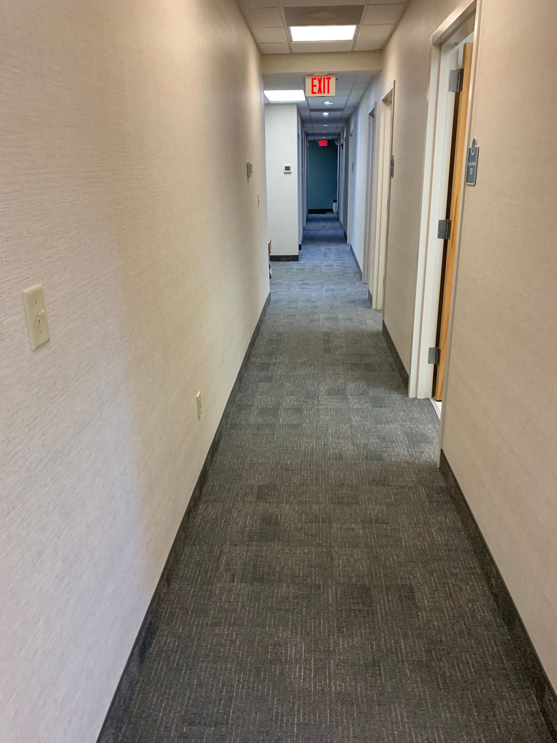 A hallway with a red exit sign on the ceiling