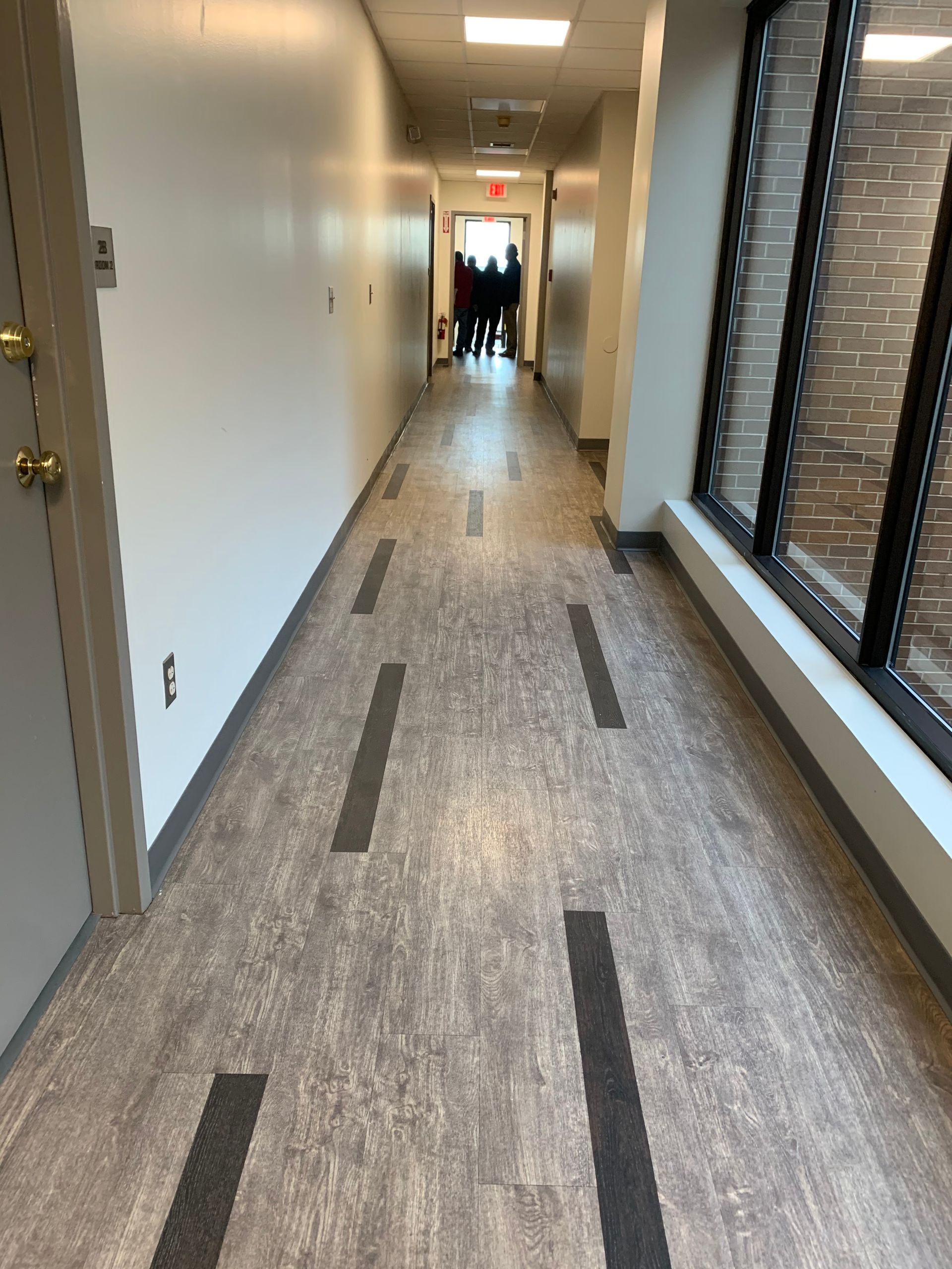 A long hallway with a lot of windows and people walking down it