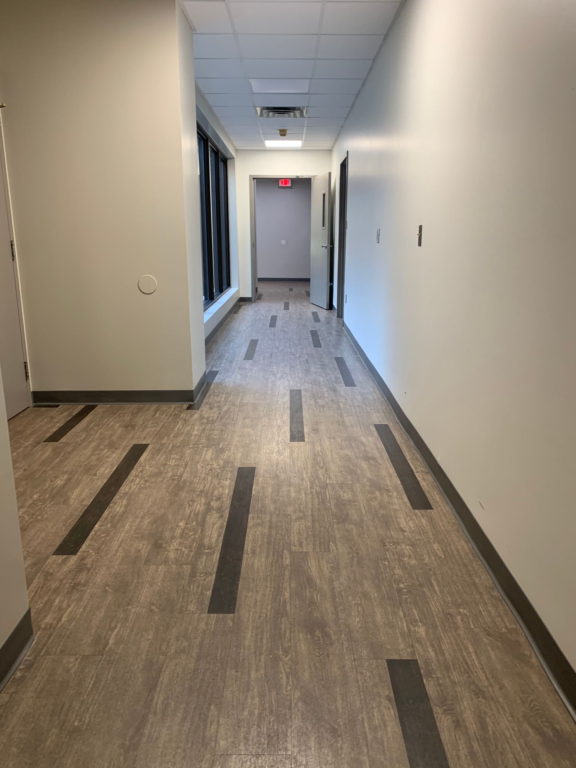 A long hallway with a wooden floor and white walls