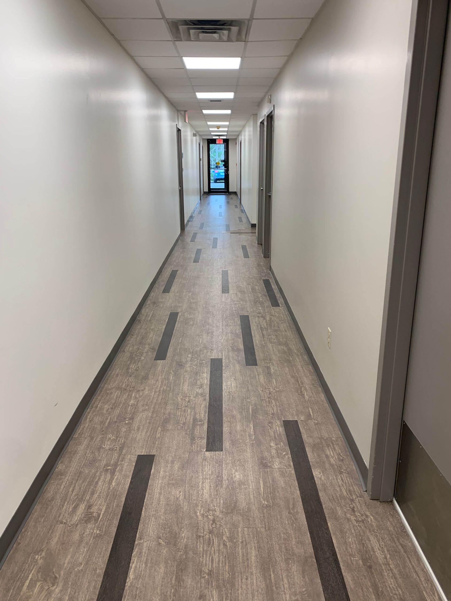 A long hallway with a brown floor and white walls