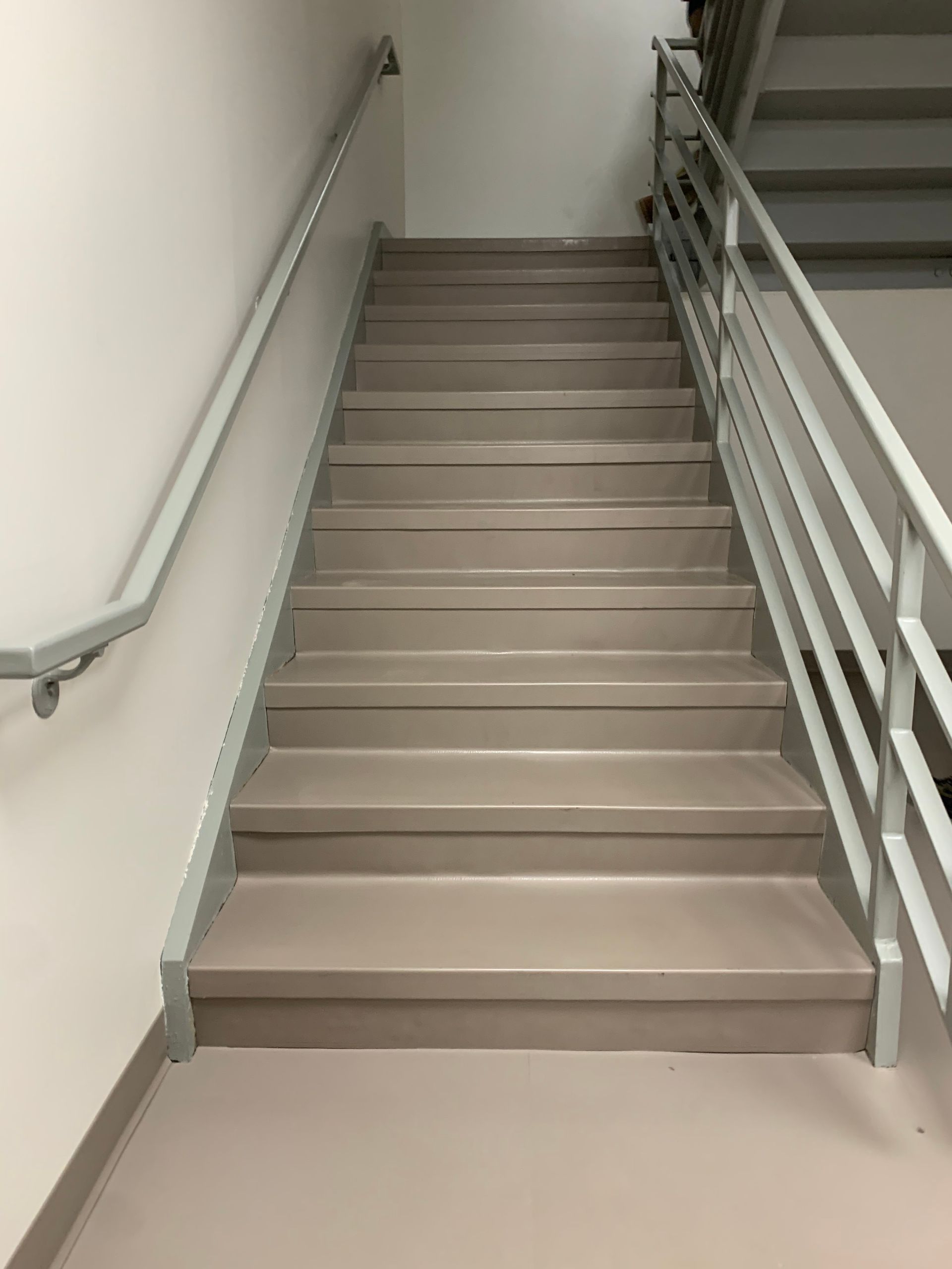 A set of stairs with a railing and a white wall