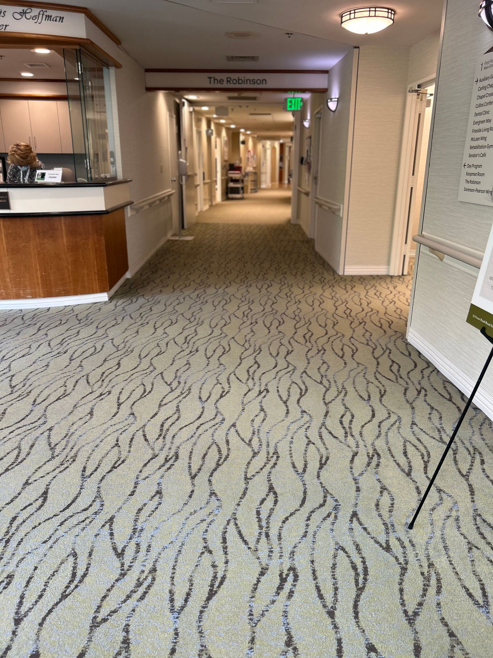 A long hallway with a carpeted floor and a reception desk