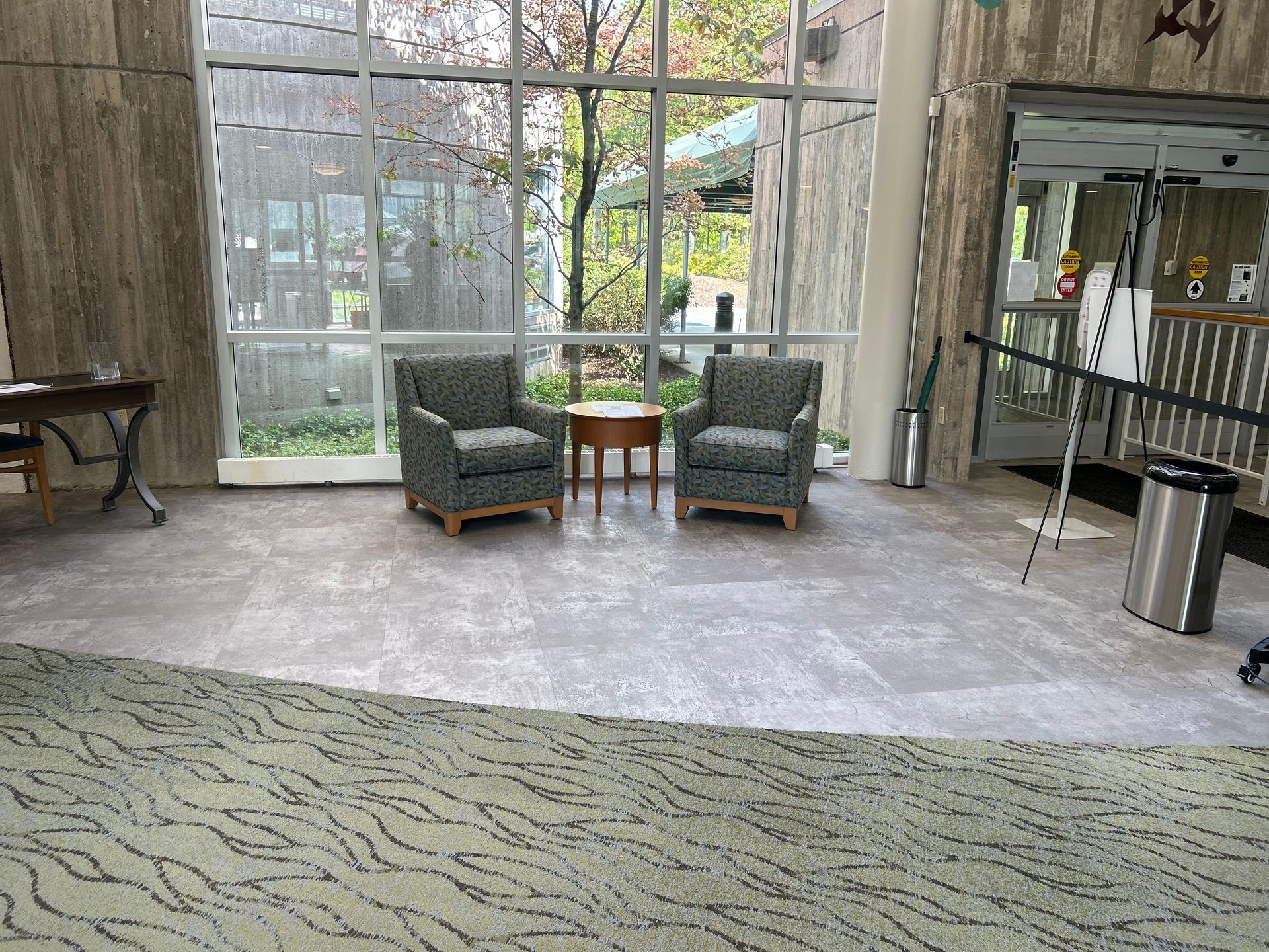 A lobby with two chairs and a table in front of a large window