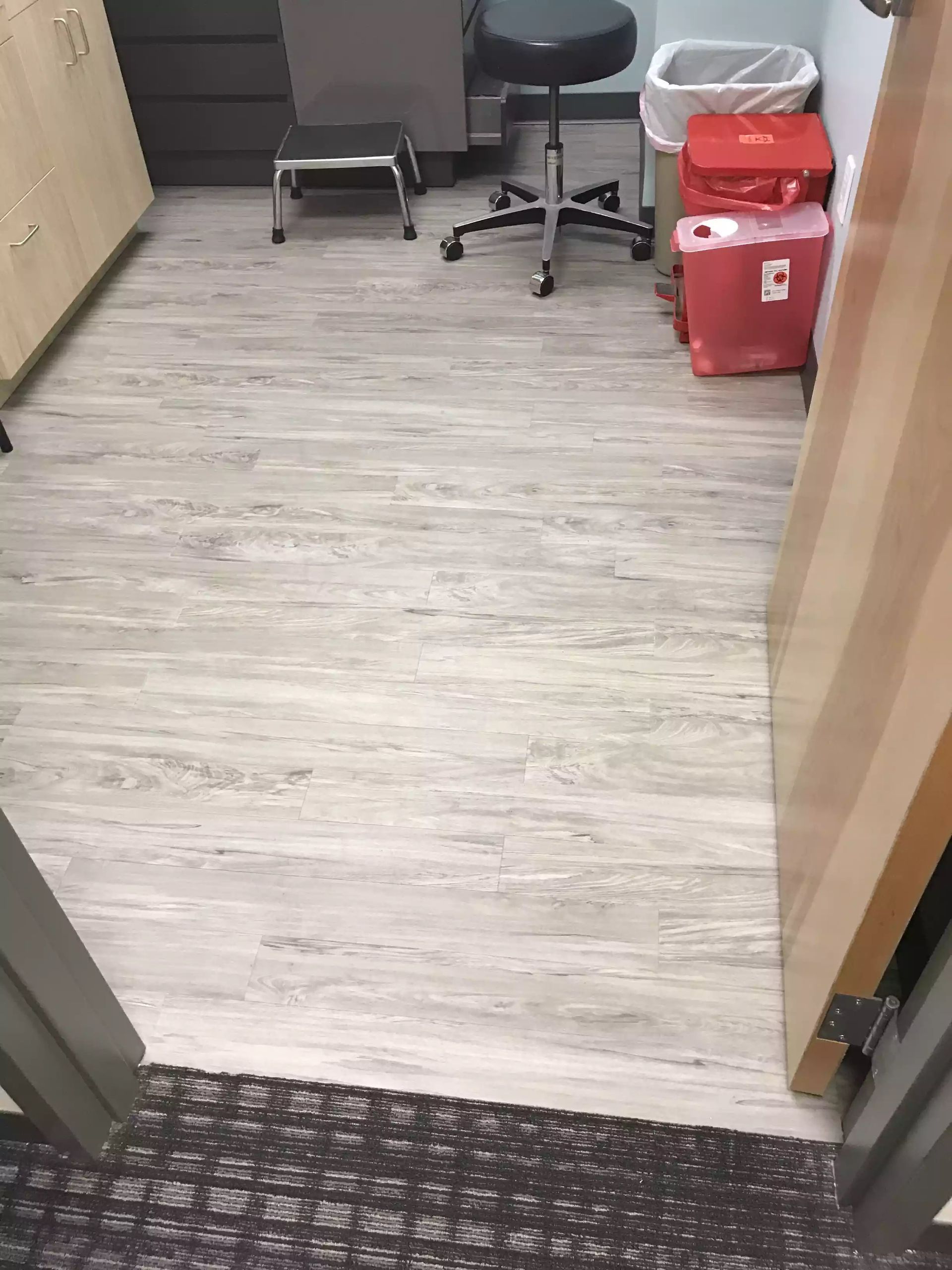 A room with a wooden floor and a stool and trash cans