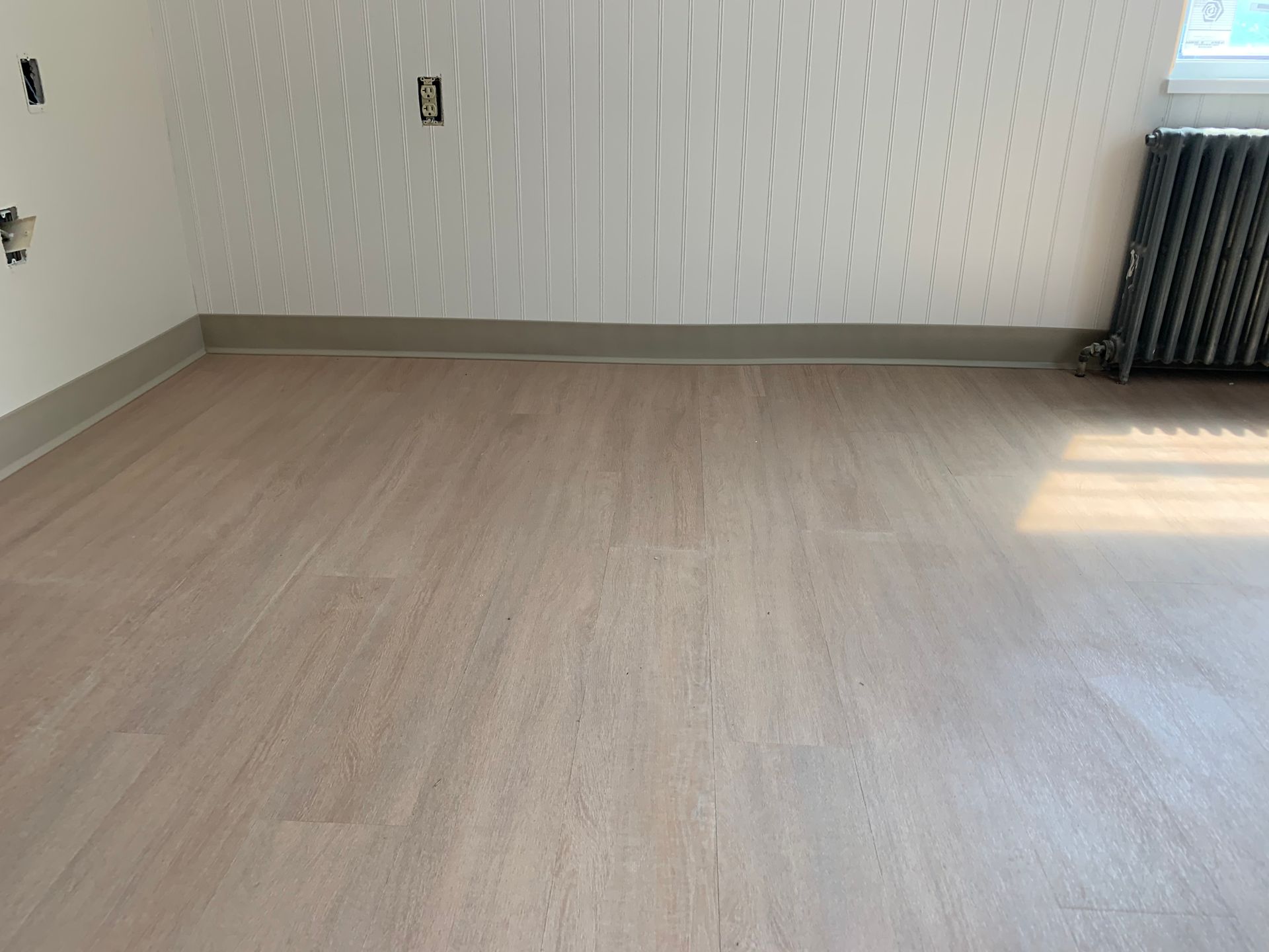 An empty room with a wooden floor and a radiator