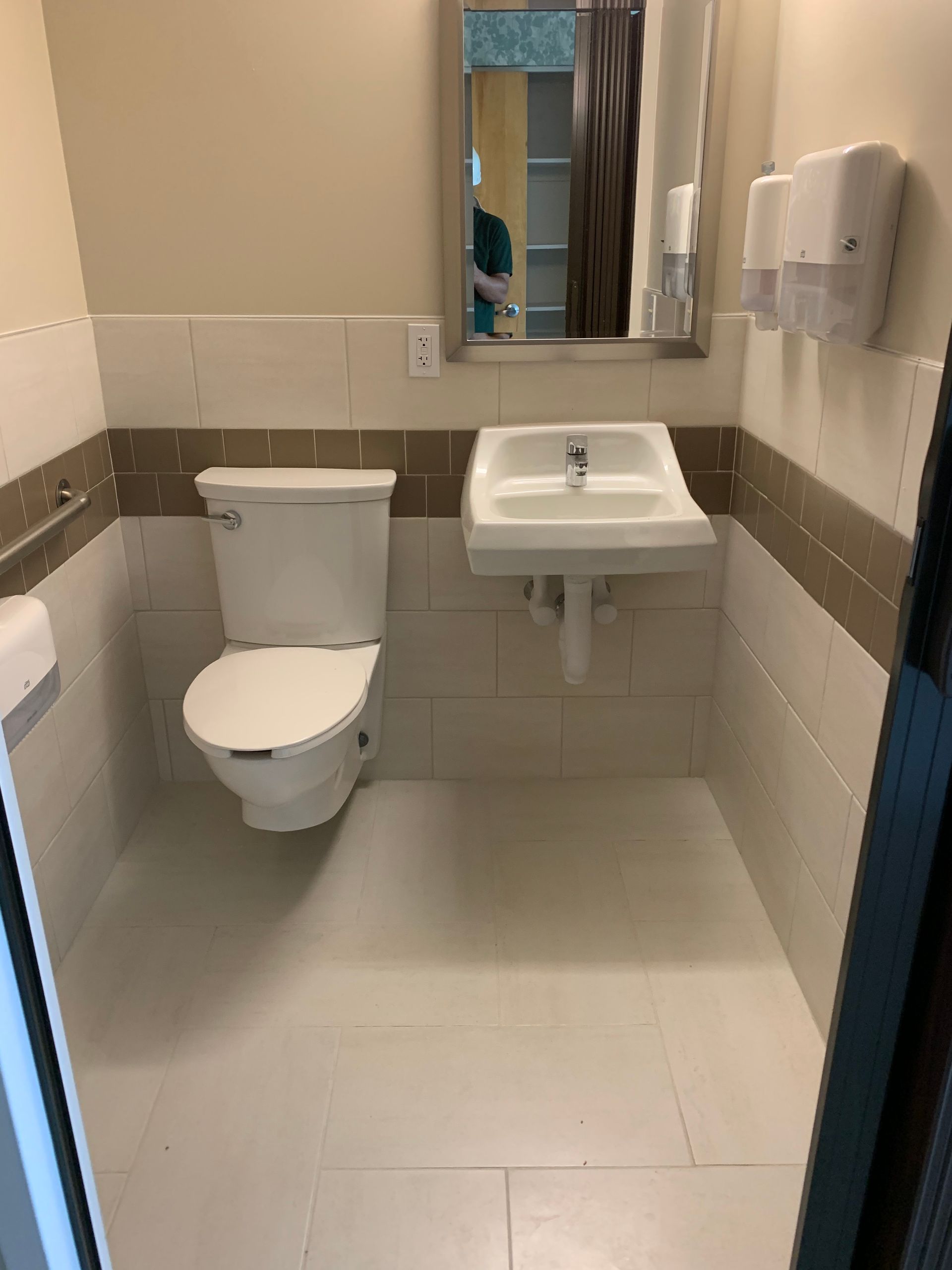 A bathroom with a toilet, sink, and mirror