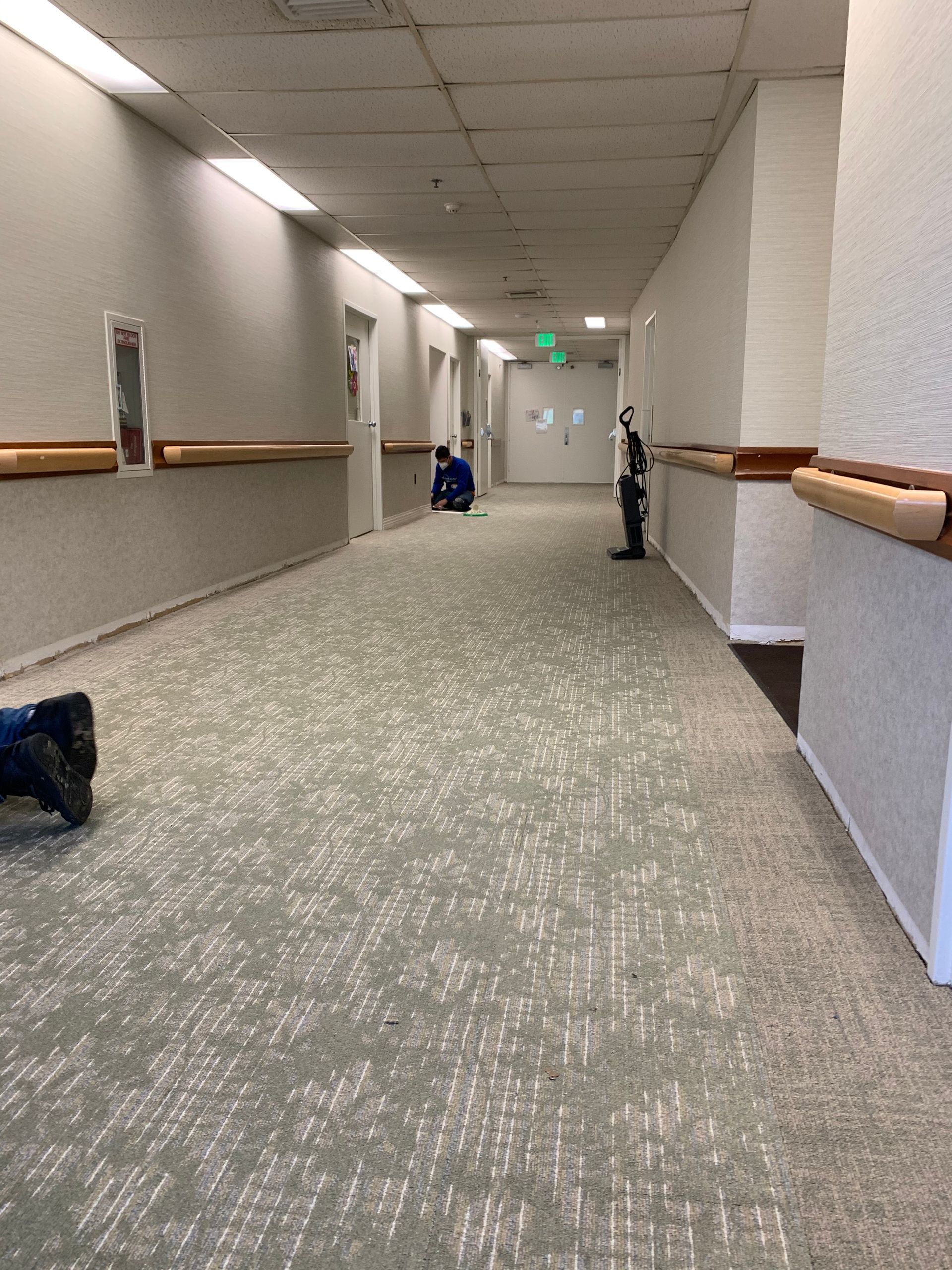 A person is laying on the floor in a long hallway