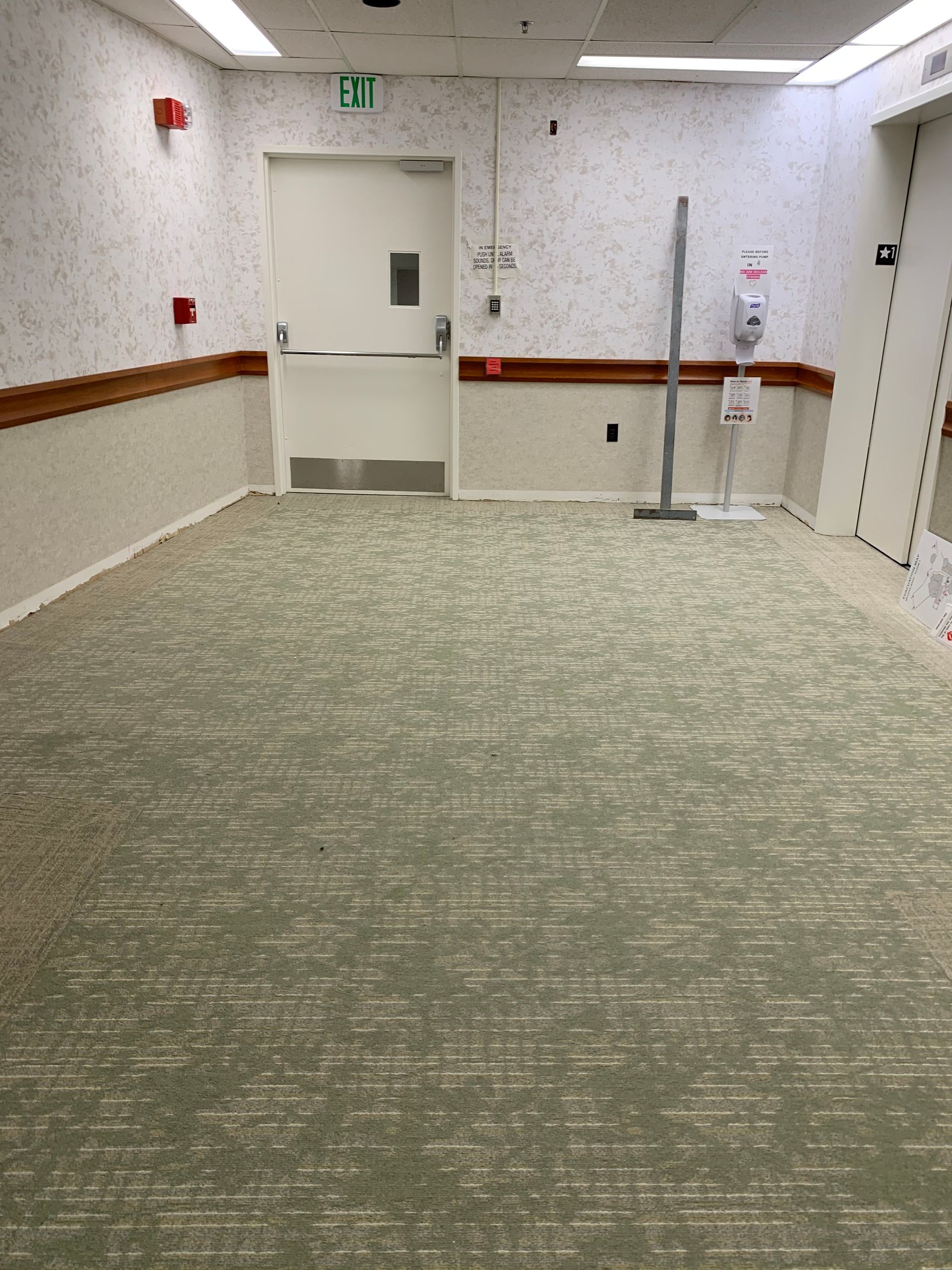 An empty room with a green exit sign on the wall