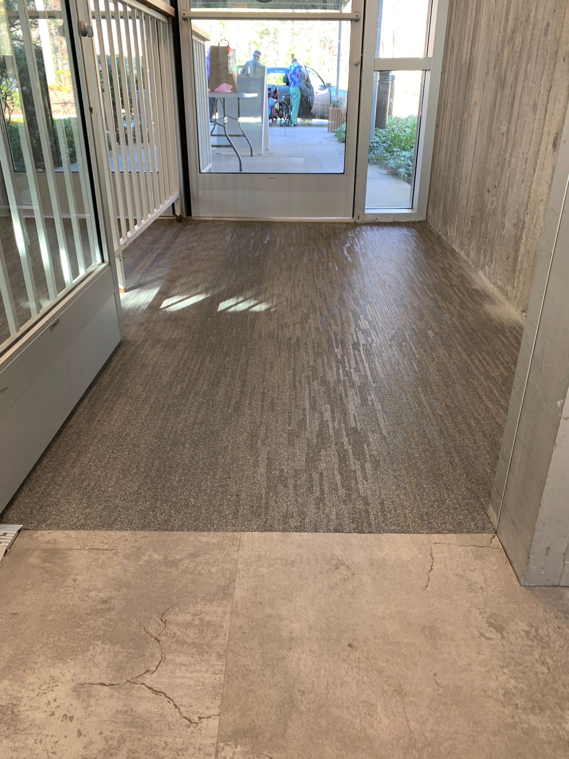 A hallway with a concrete floor and a glass door leading to a balcony