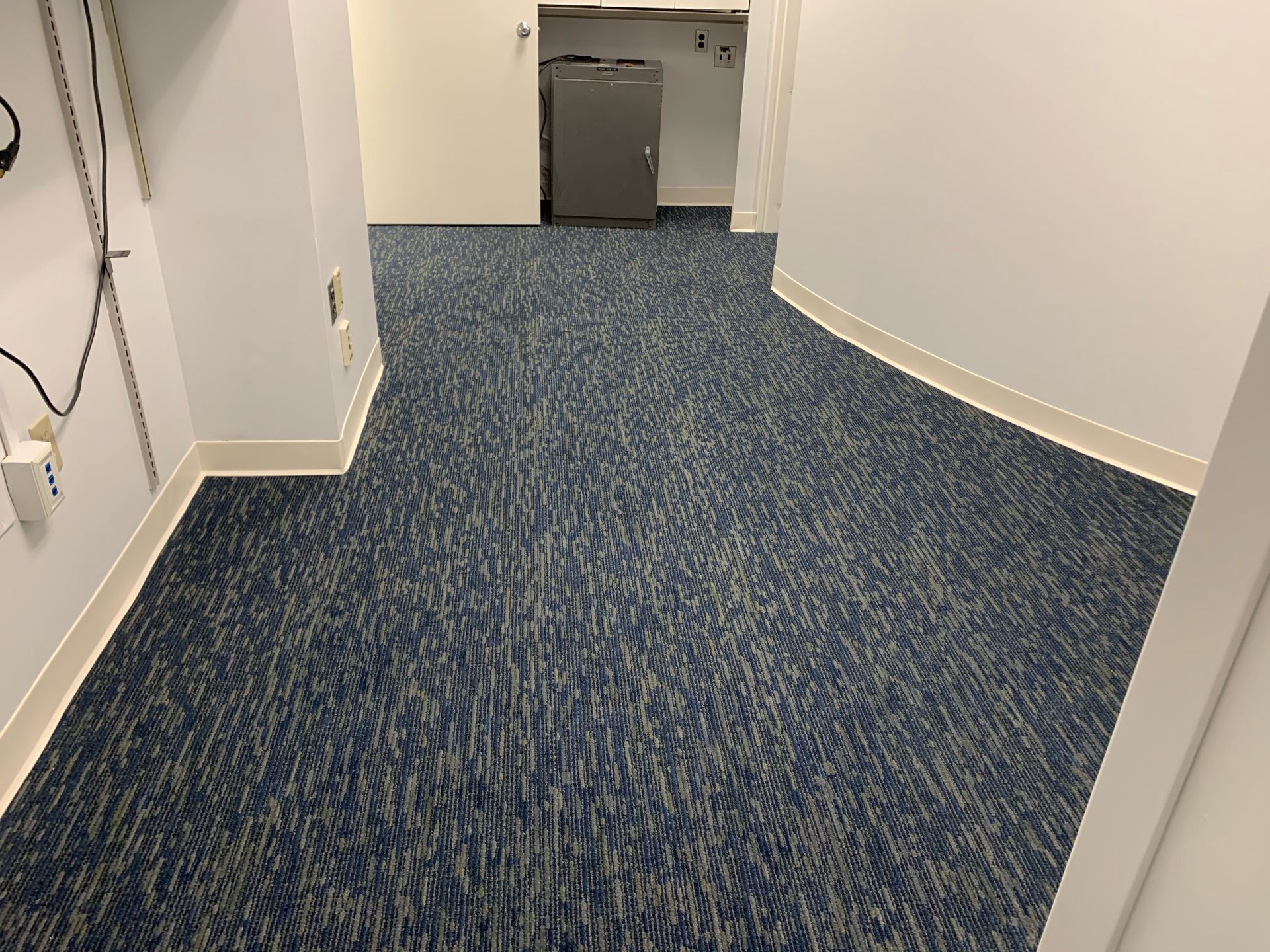 A room with a blue carpeted floor and white walls