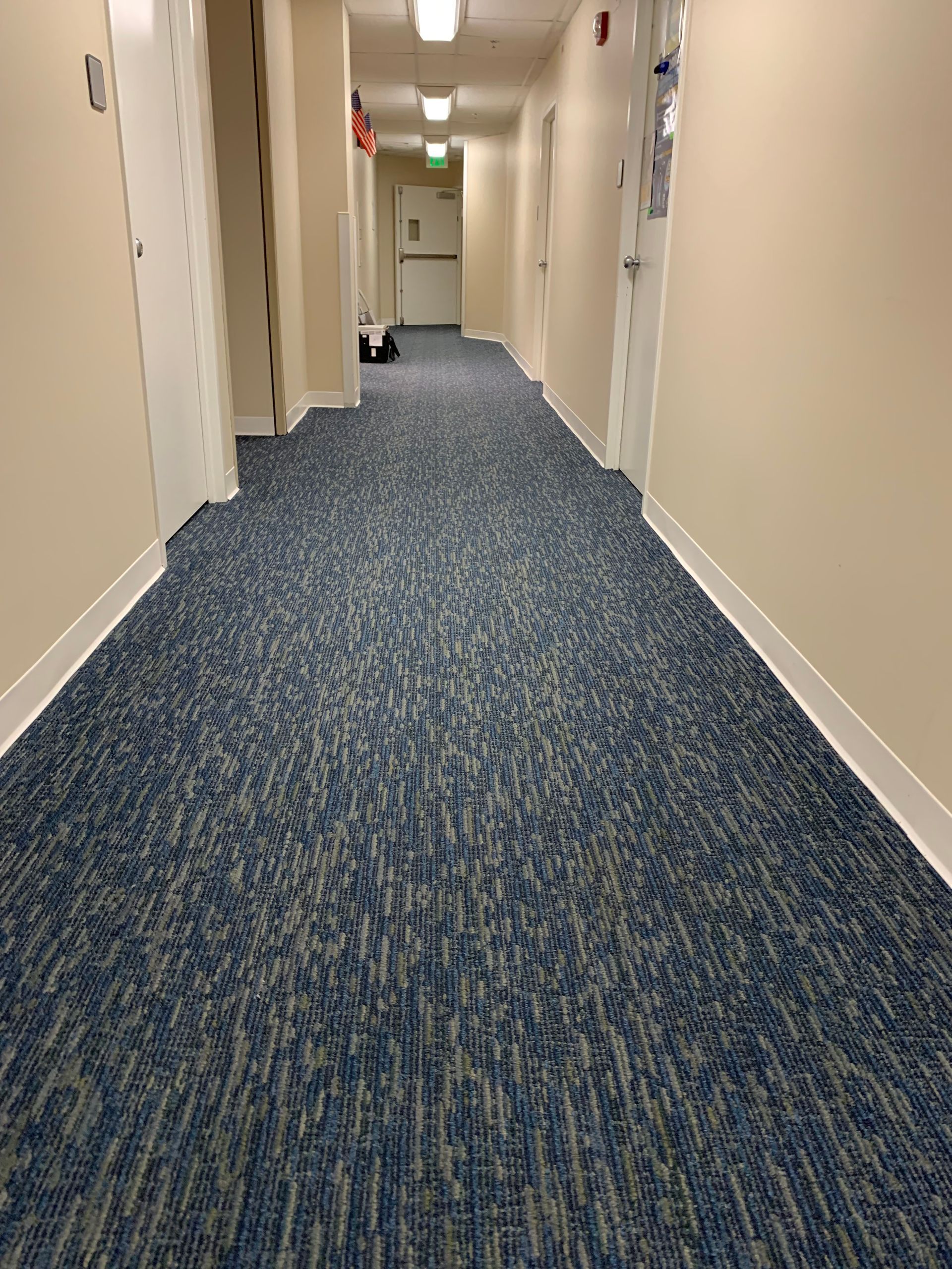 A long hallway with blue carpet and white walls