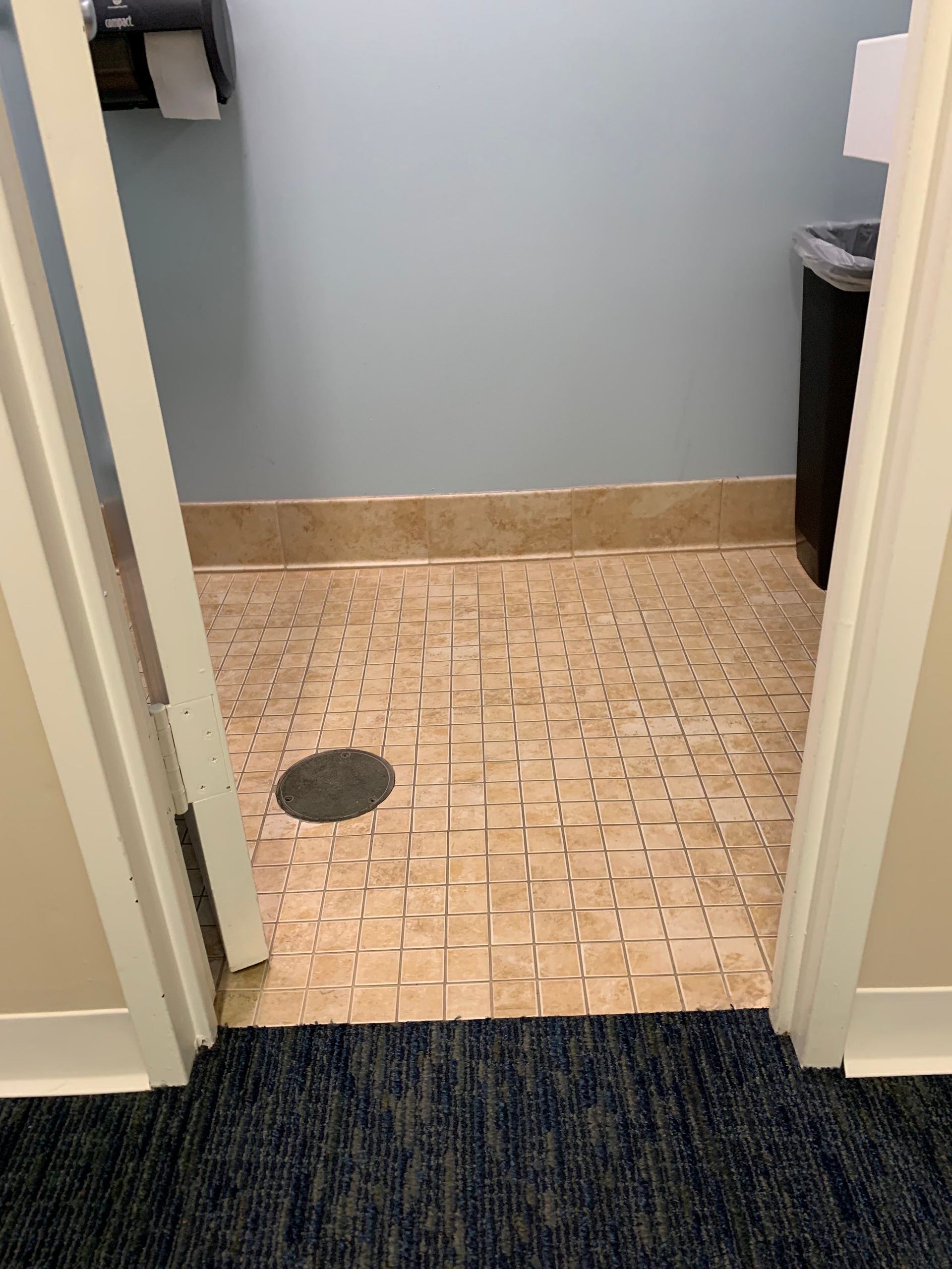 A doorway leading to a bathroom with a drain on the floor