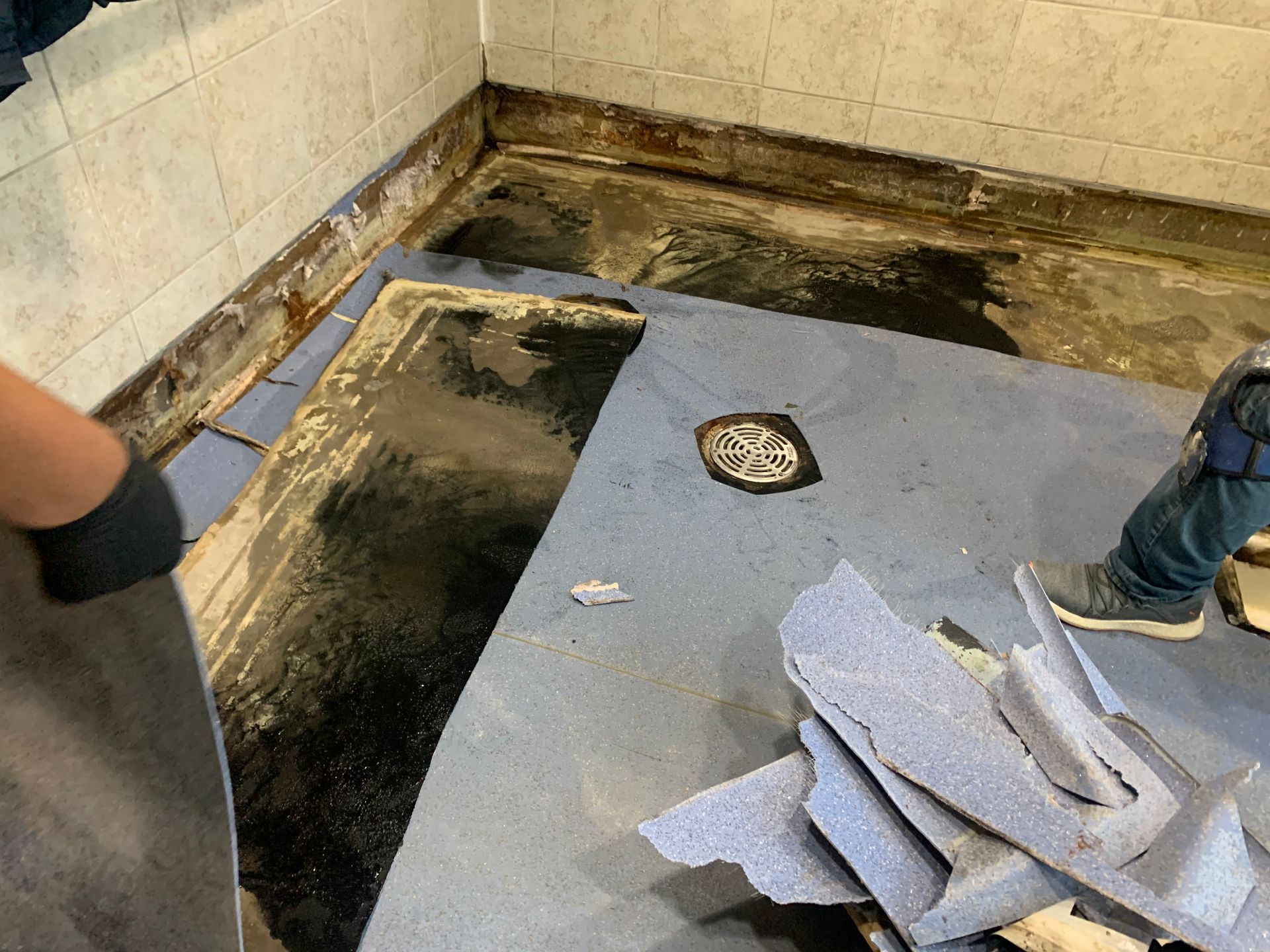 A person is removing a carpet from a bathroom floor