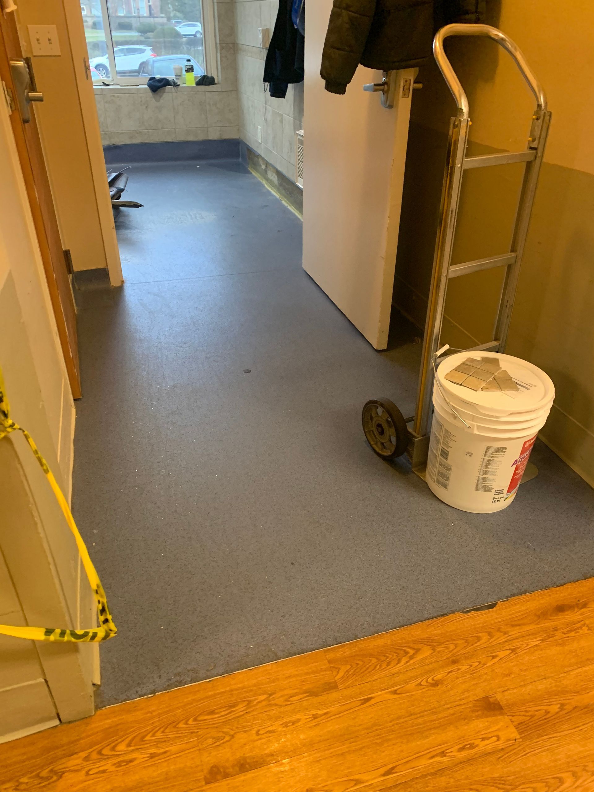 A white bucket is on a cart in a hallway