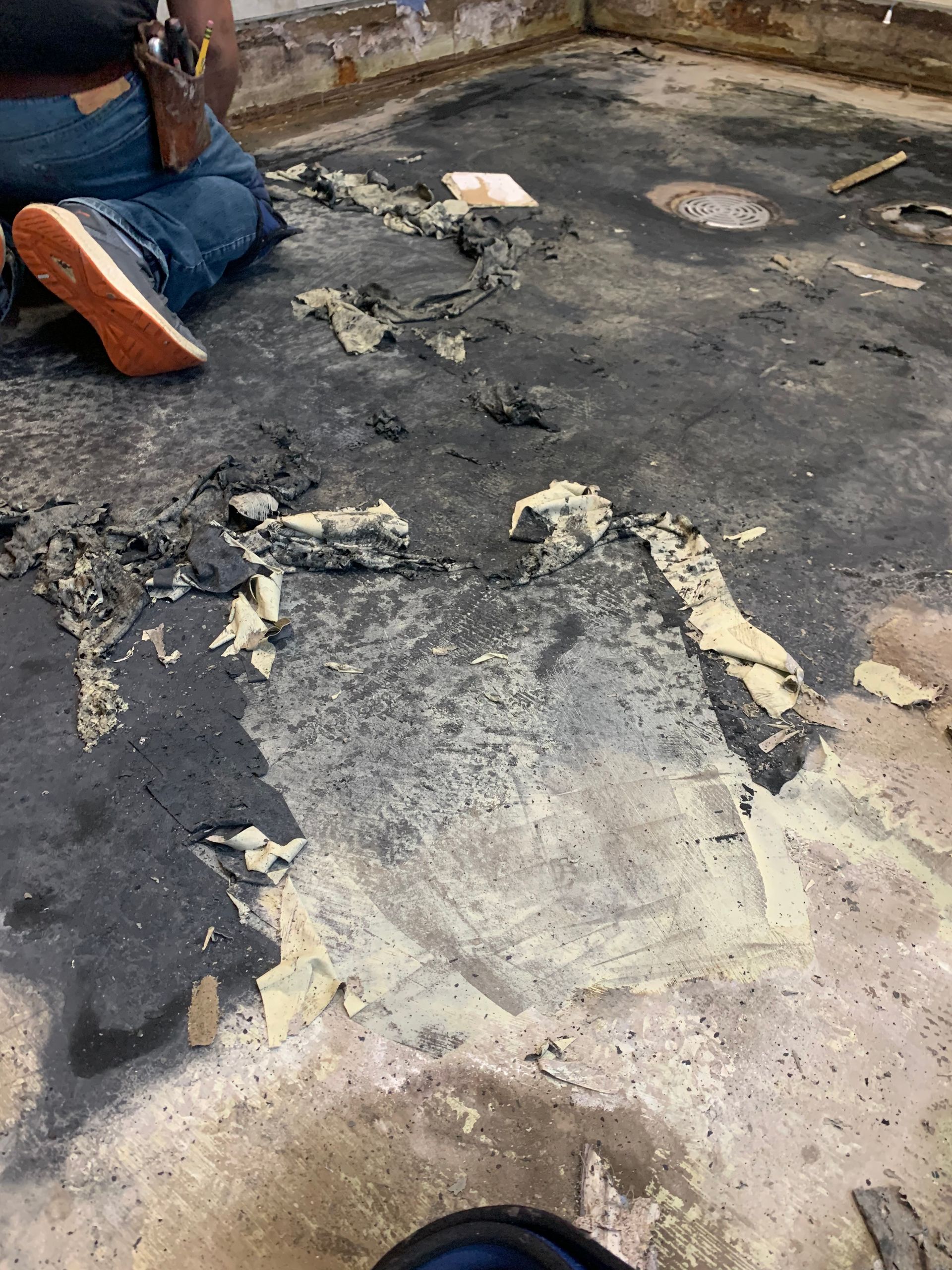 A person is kneeling on a dirty concrete floor