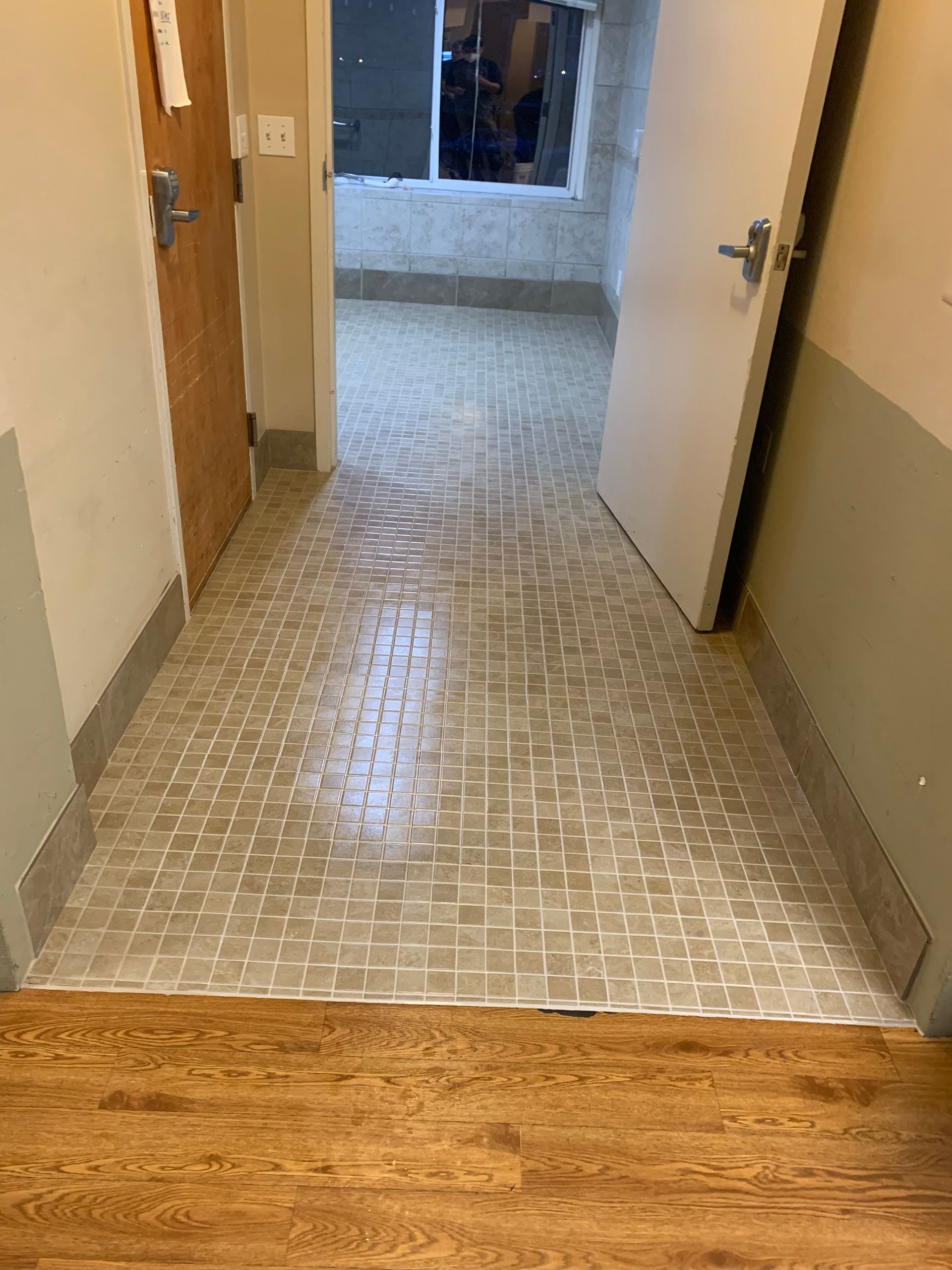 A hallway with a wooden floor and a door leading to a bathroom
