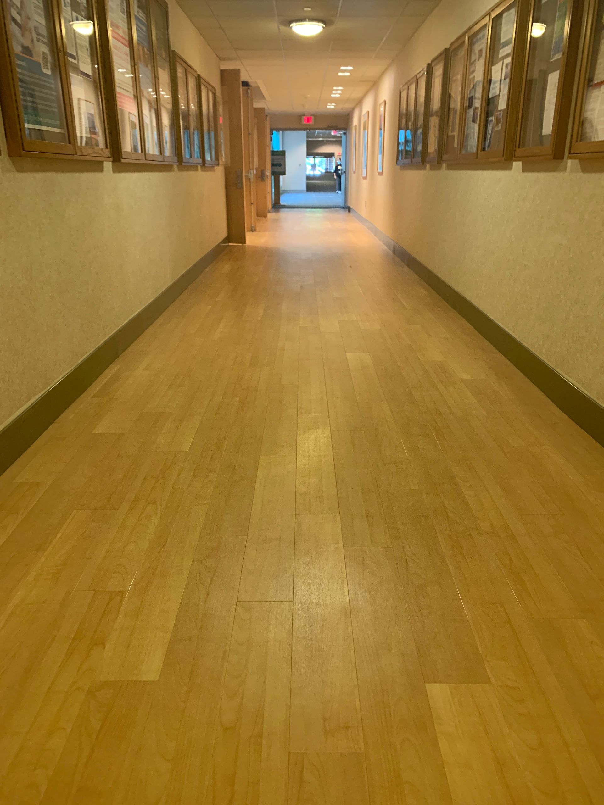 A long hallway with wooden floors and pictures on the wall