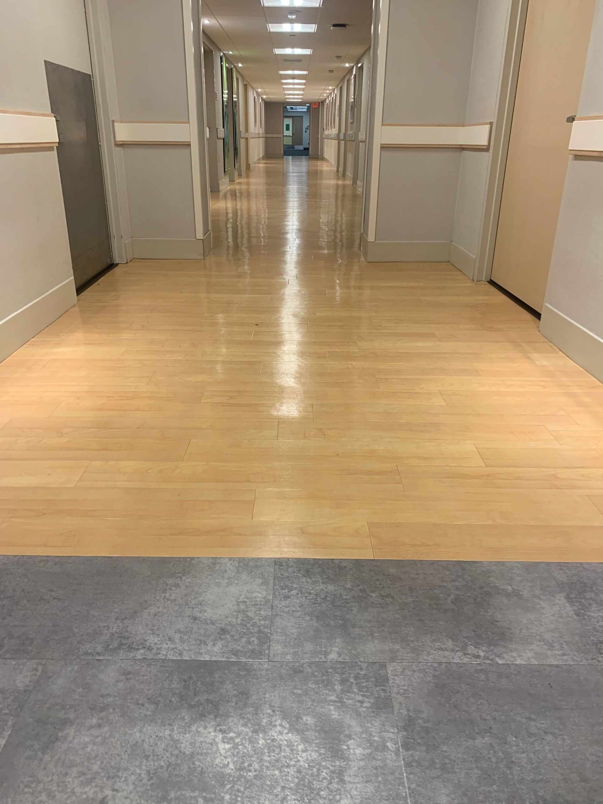 A long hallway in a hospital with wooden floors