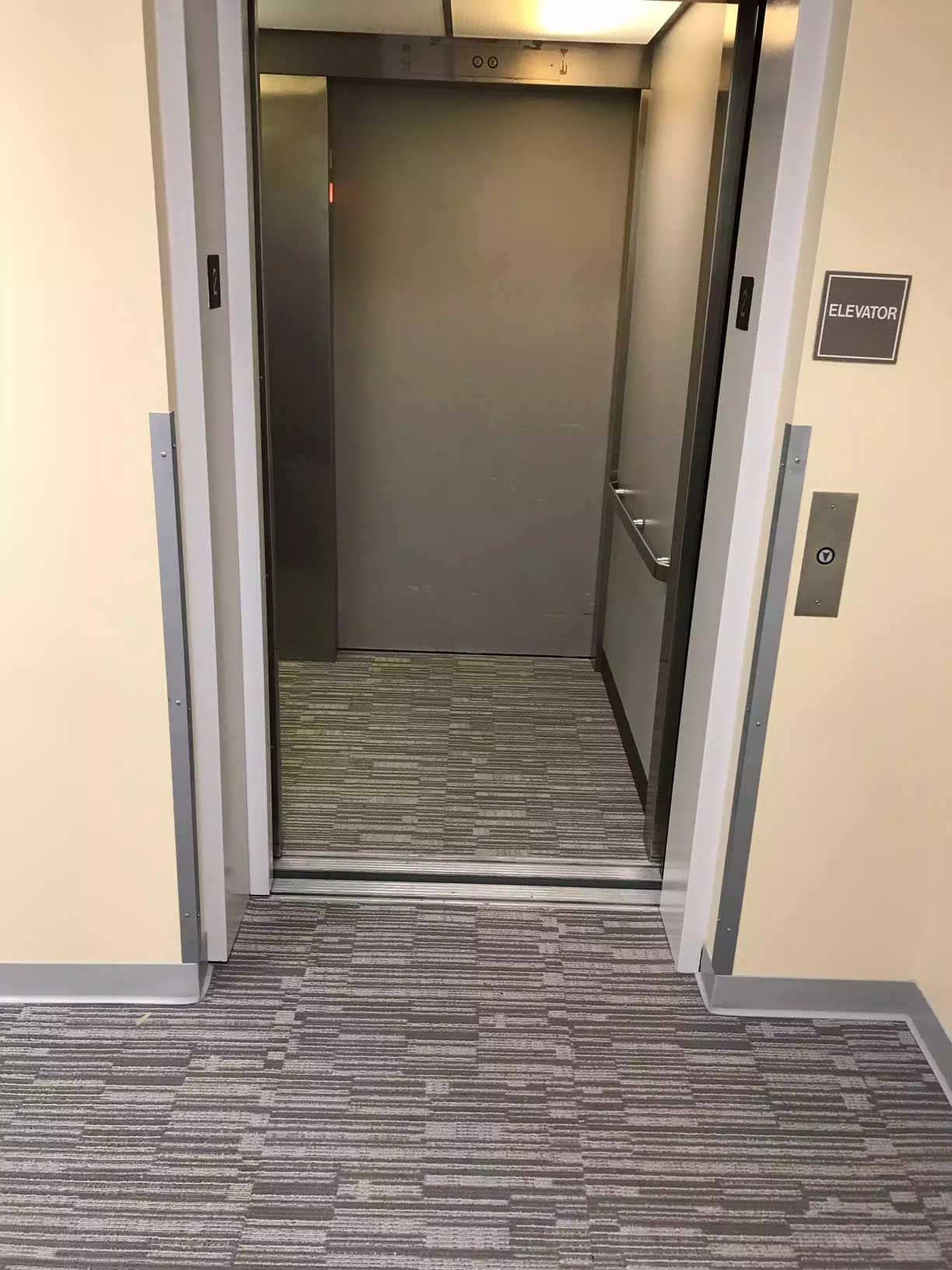 A hallway with a carpeted floor and a carpeted elevator