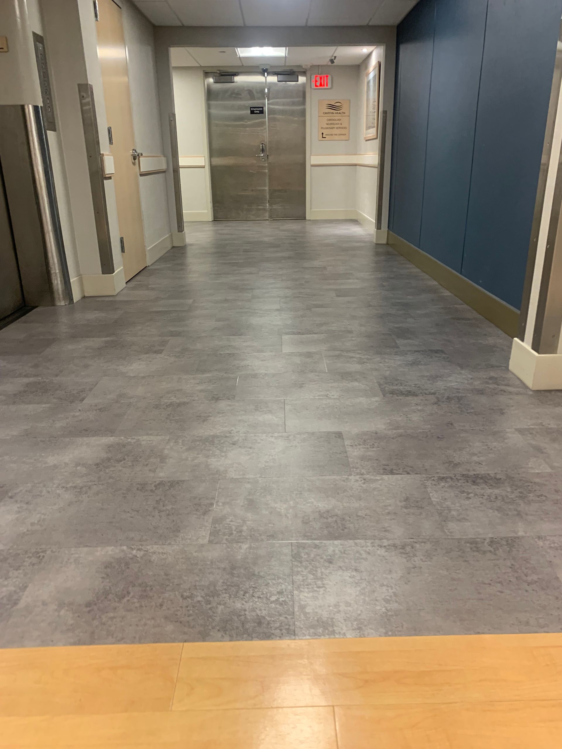 A hallway with a gray tile floor and a blue wall.