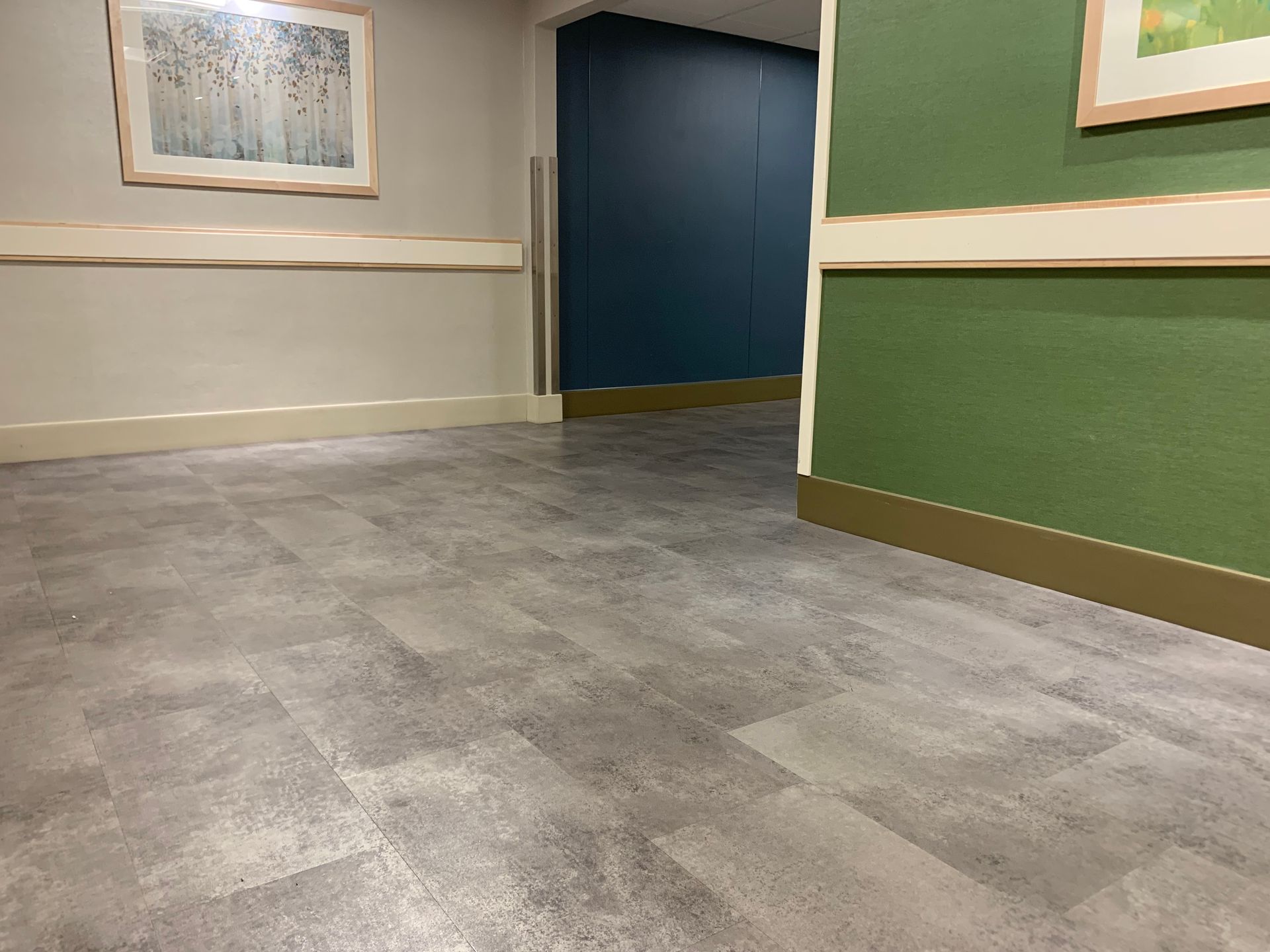 A hallway with a gray floor and green walls.