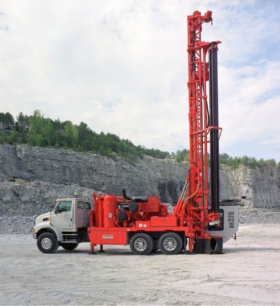 A white truck with a red drill attached to it