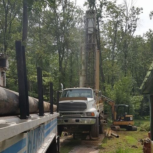 A truck is driving down a dirt road in the woods.