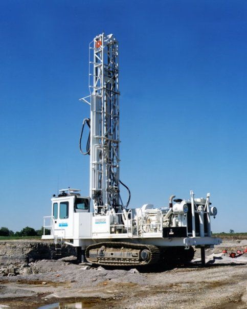 A large white machine is sitting on top of a dirt field.