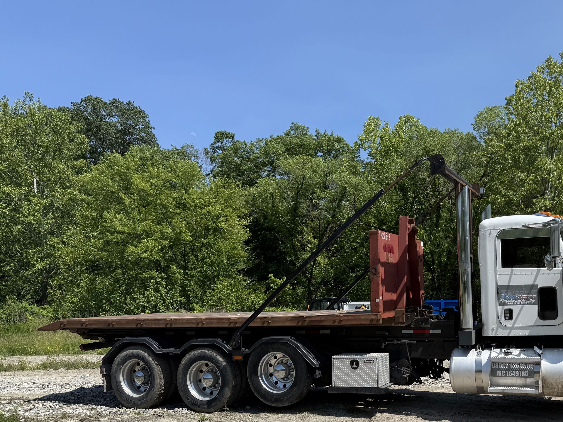 A dump truck with a flatbed is parked on the side of the road.