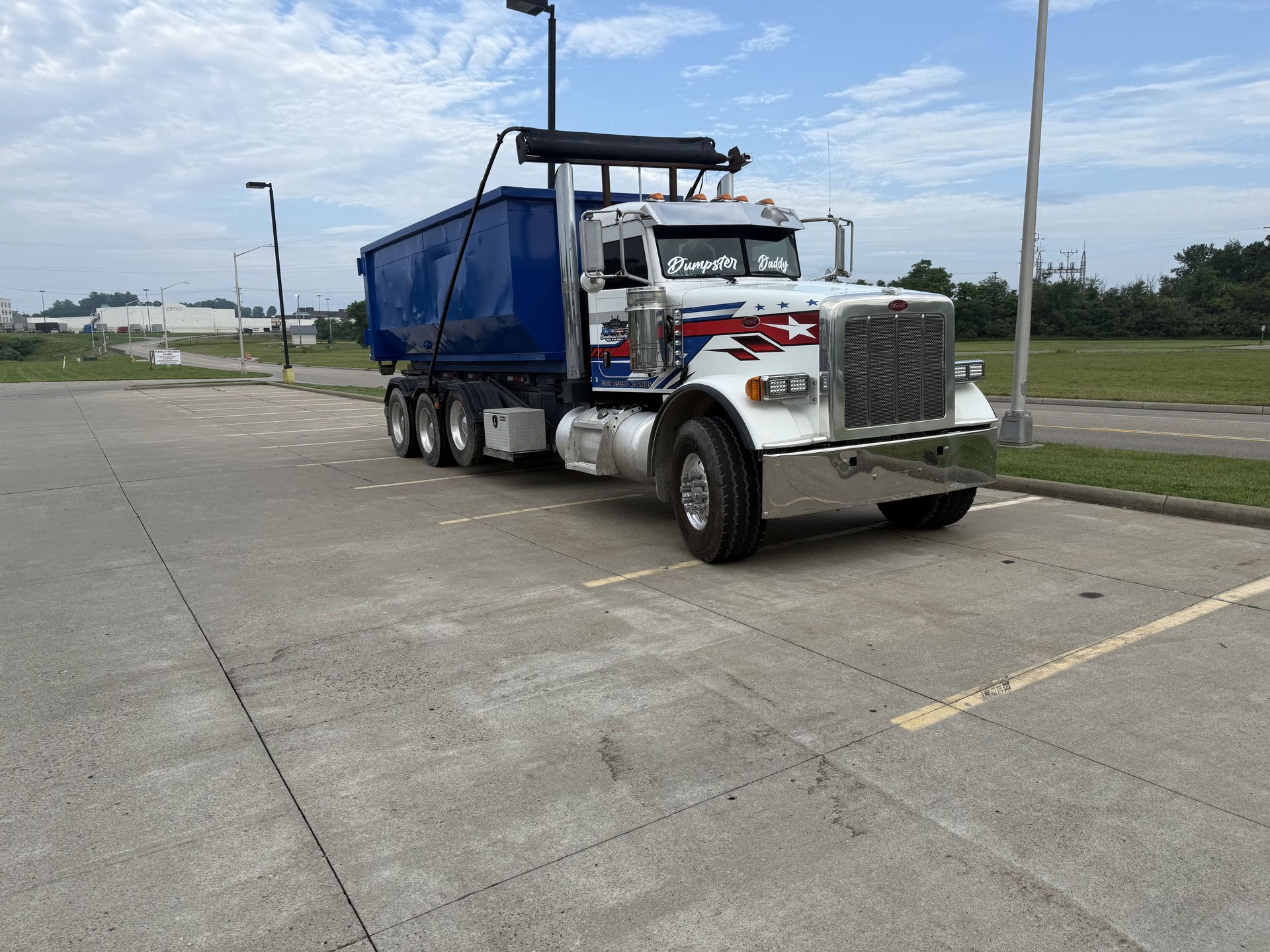 A blue and white dump truck is parked in a parking lot.