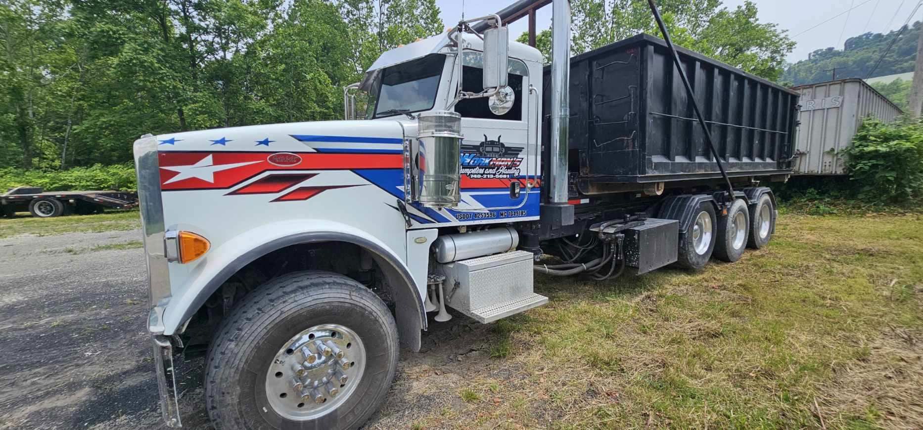 A dump truck is parked in a grassy field.