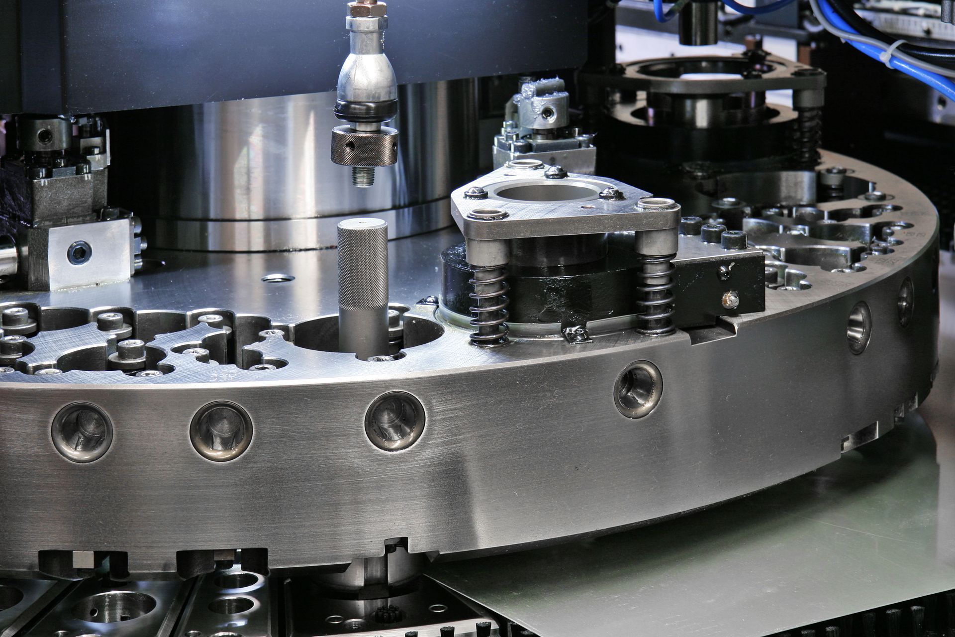 Close-up of a circular industrial machine with various metal components and cylindrical parts.