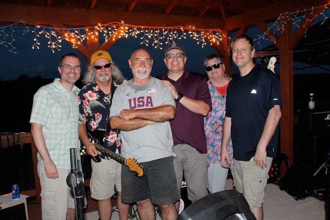 A group of men are posing for a picture with one man wearing a USA shirt.