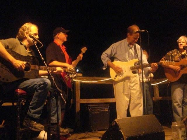 A group of men are playing guitars and singing into microphones on a stage.