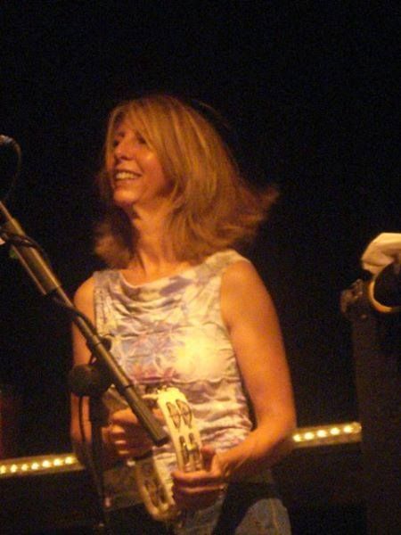 A woman playing a tambourine in front of a microphone.