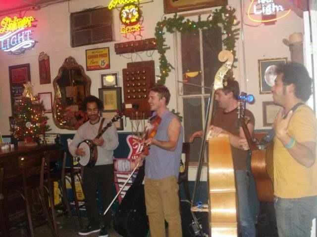 A group of men playing instruments in front of a bud light sign.