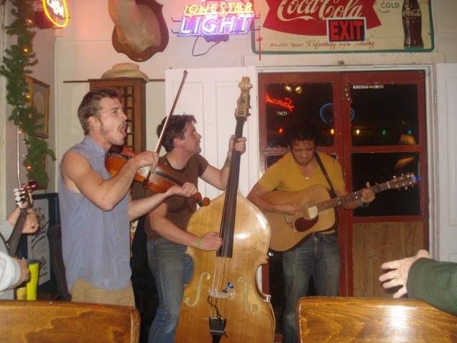 A group of men are playing instruments in front of a Coca-Cola sign.