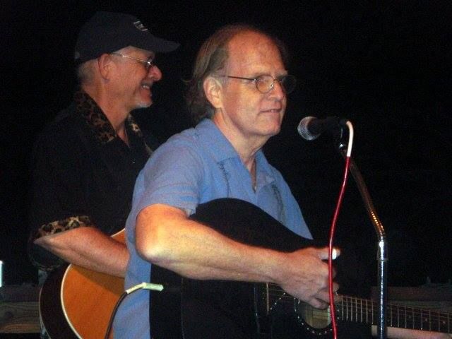 A man playing a guitar and singing into a microphone.