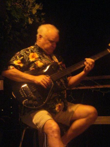 A man in a floral shirt is playing a guitar.