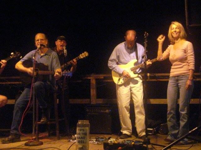 A group of people playing guitars and singing on a stage.