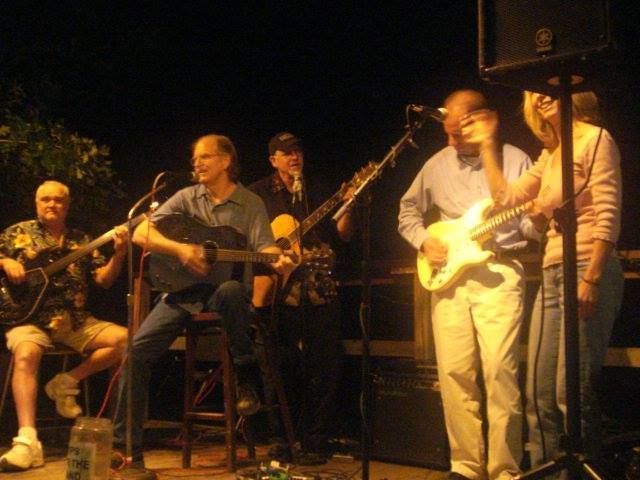 A group of people playing guitars and singing into microphones.