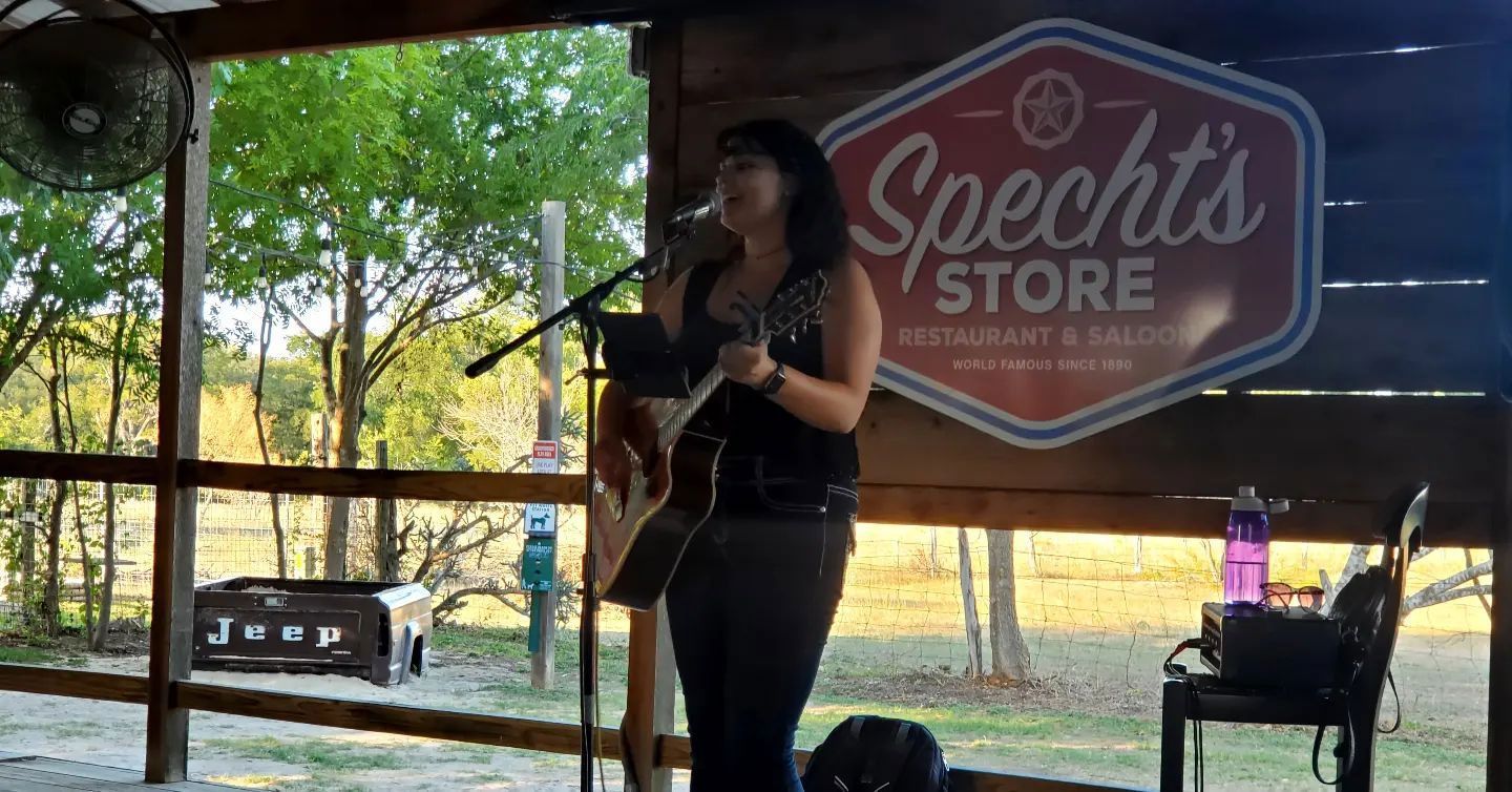 A woman is singing into a microphone while playing a guitar.