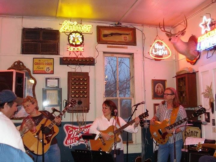 A group of people playing guitars in front of a Bud Light sign.