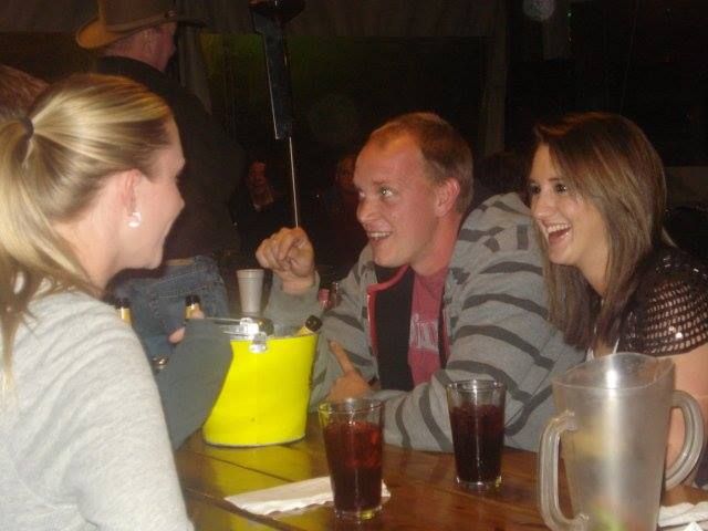 A group of people are sitting at a table with a pitcher of soda.