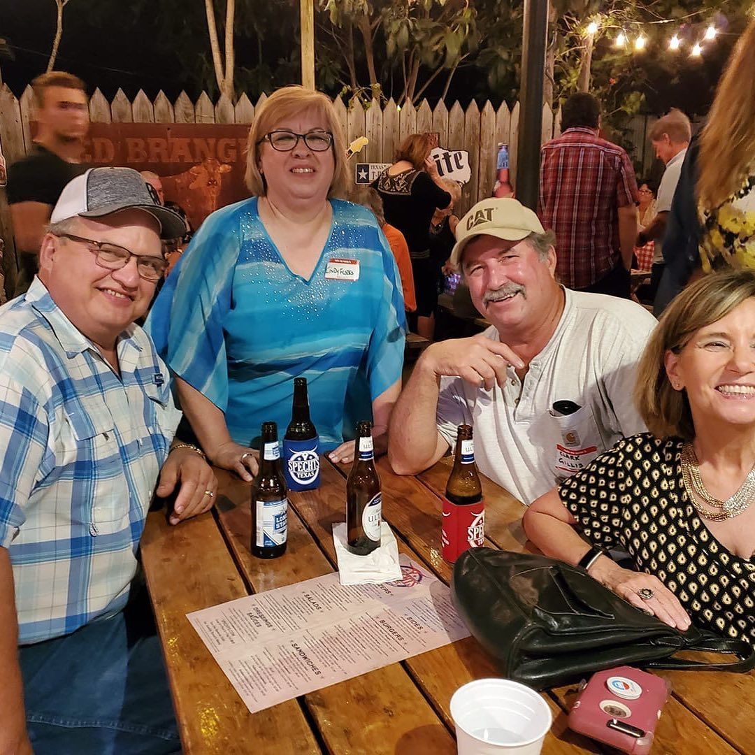 A group of people are sitting at a table with bottles of beer.